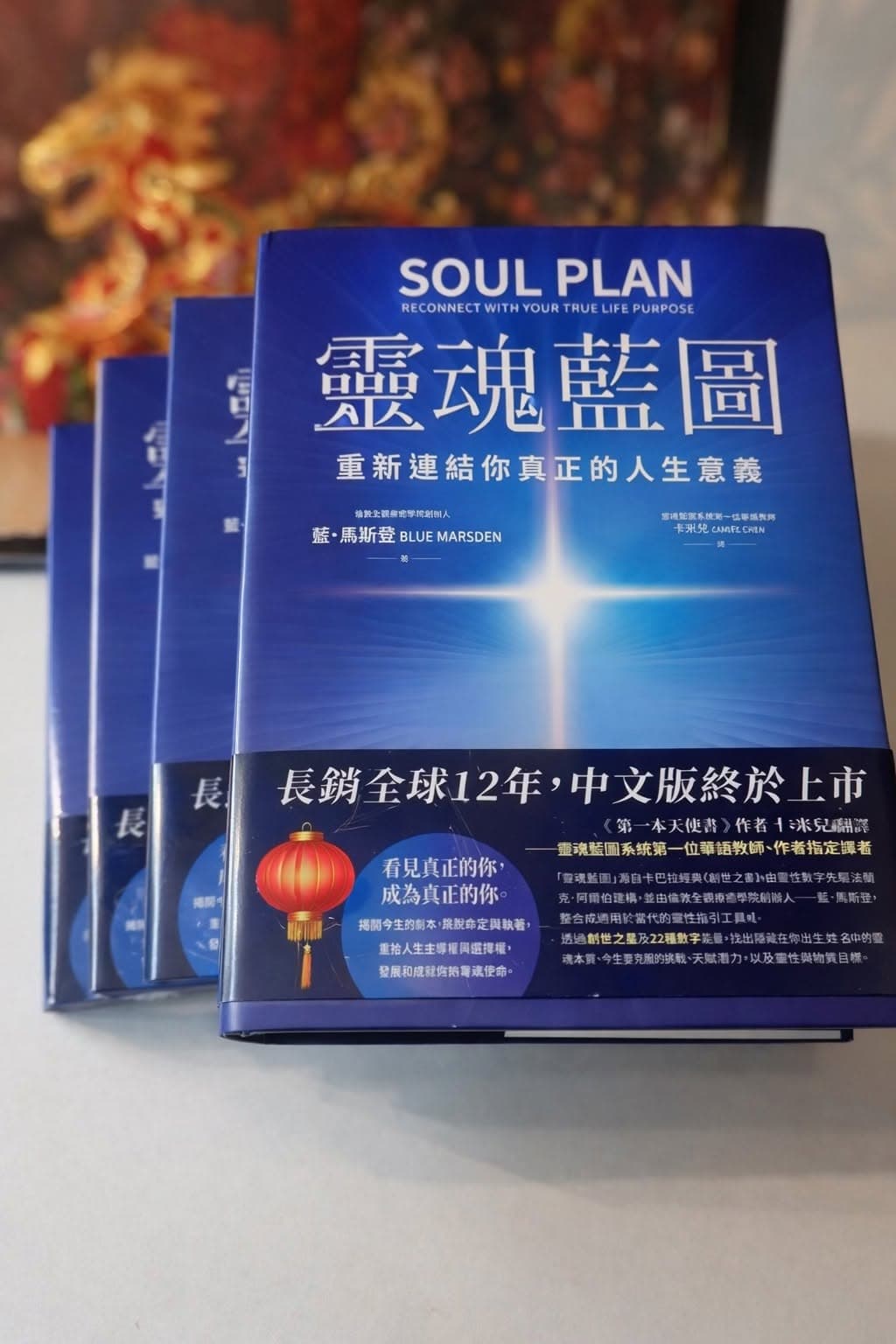 A stack of the first Chinese edition of Soul Plan — 靈魂藍圖 by Blue Marsden — its deep blue cover lit by a bright star, a red lantern behind.